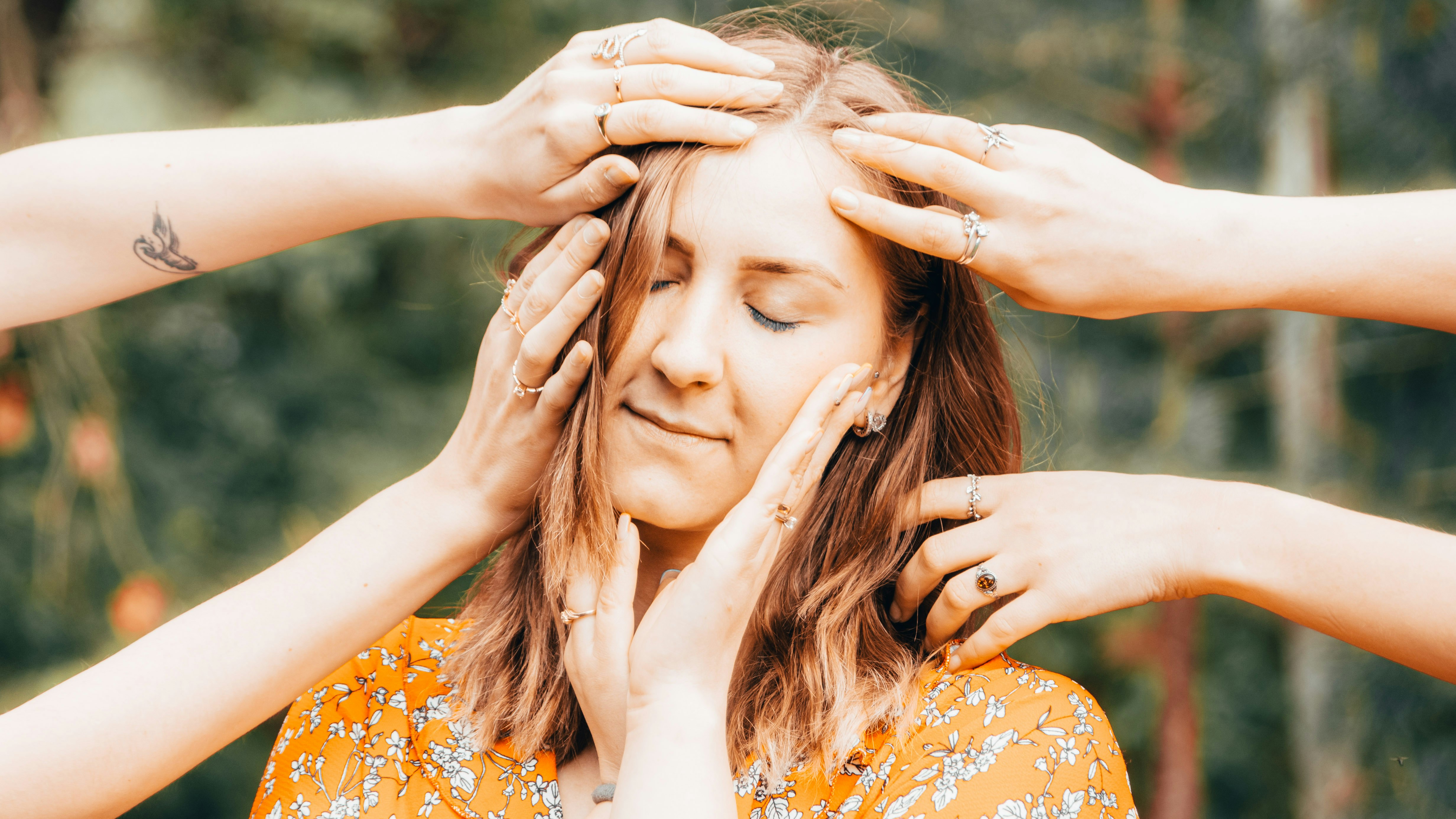 woman in orange and white floral dress covering her face with her hands